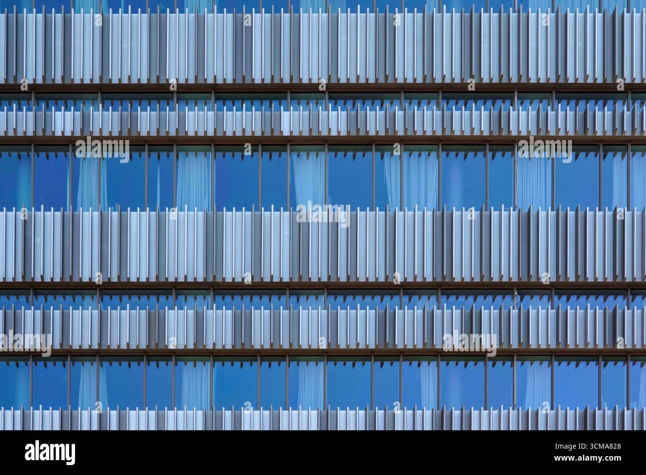 Armonia architettonica: Pinne moderne. All'Università di Malmö in Svezia, la facciata combina pinne verticali grigio-bianche con finestre in vetro blu, creando ritmo, trasparenza e modulazione della luce solare, migliorando al contempo l'armonia geometrica. Foto Stock