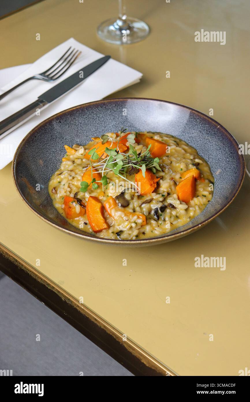 risotto cremoso e gourmet. Il ricco riso dorato è mescolato con funghi terrosi e pezzi di zucca di zucca con nocciole. Foto Stock