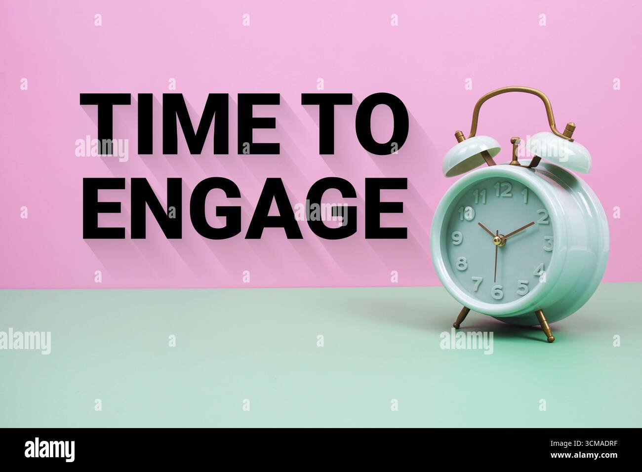 Sveglia nera su sfondo verde pastello e rosa con il testo "Time to Engage" Foto Stock