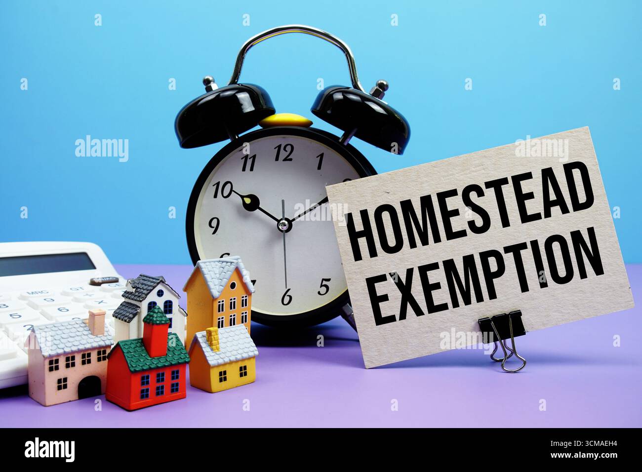 Frase di esenzione Homestead con calcolatrice, sveglia, modello case concetto finanziario immobiliare Foto Stock