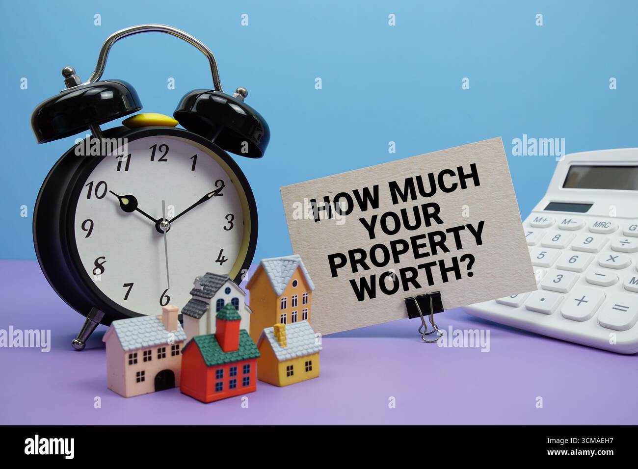 Quanto vale la sua proprietà? Frase con calcolatrice, sveglia, modello di case concetto finanziario immobiliare Foto Stock