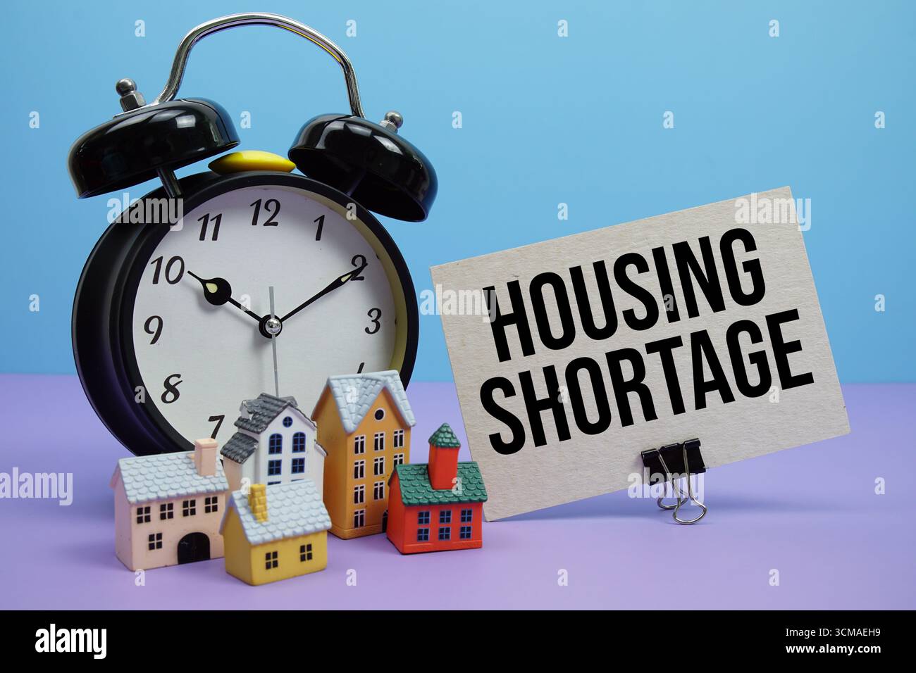 Frase relativa alla carenza di alloggi con calcolatore, sveglia, modello di case concetto finanziario immobiliare Foto Stock