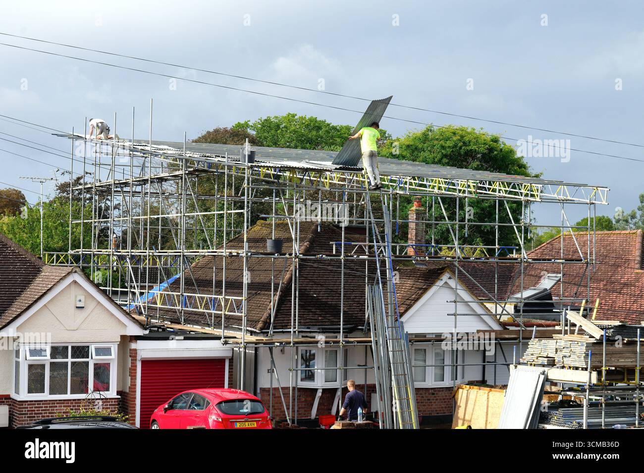 Scaffolders che erigono una copertura impermeabile su un bungalow periferico prima che vengano eseguiti importanti lavori di costruzione, Shepperton, Surrey, Inghilterra Foto Stock