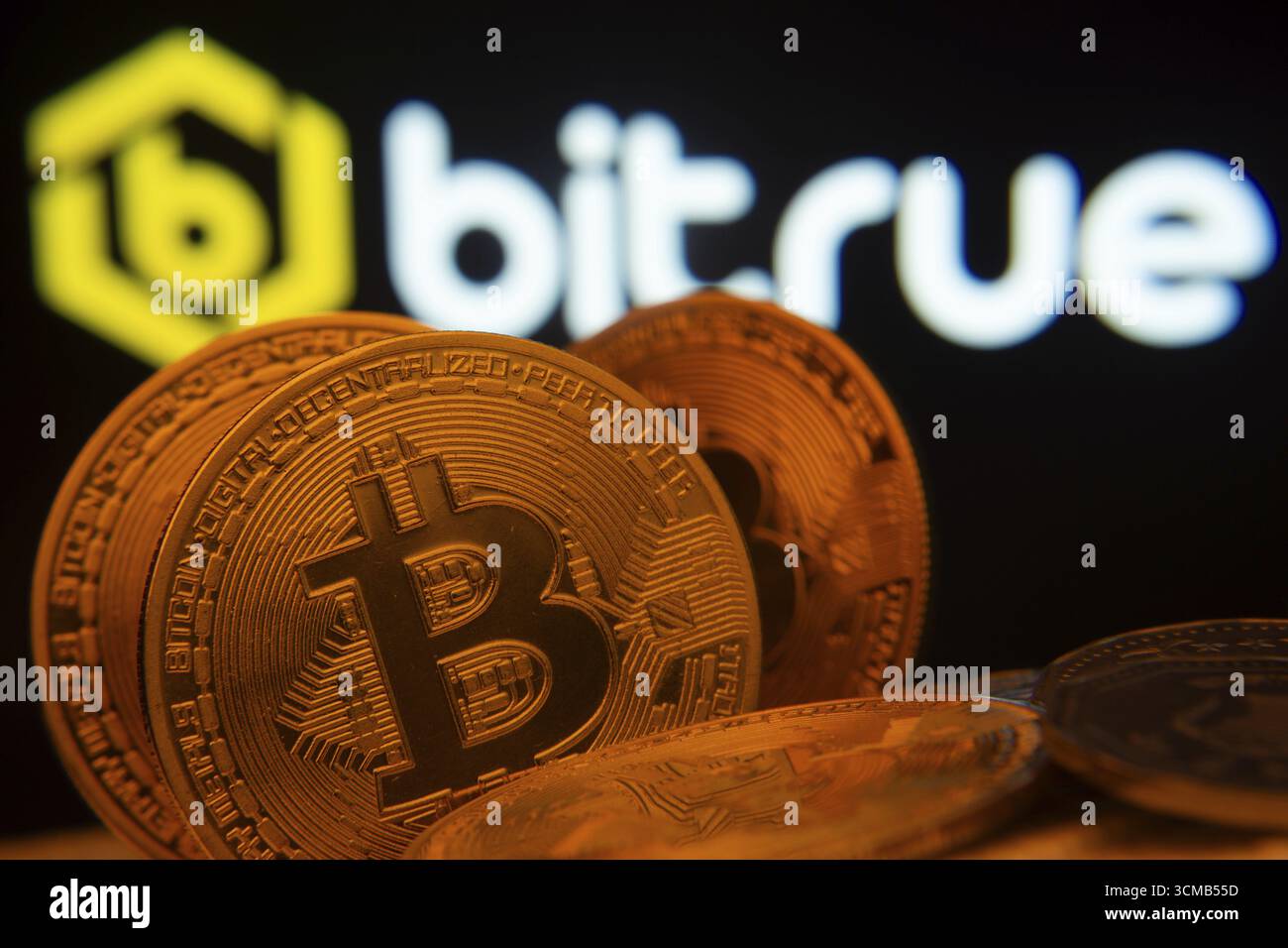Dhaka, Bangladesh- 03 set 2025: Primo piano delle monete Bitcoin con il logo Bitrue visibile su uno schermo sullo sfondo Foto Stock