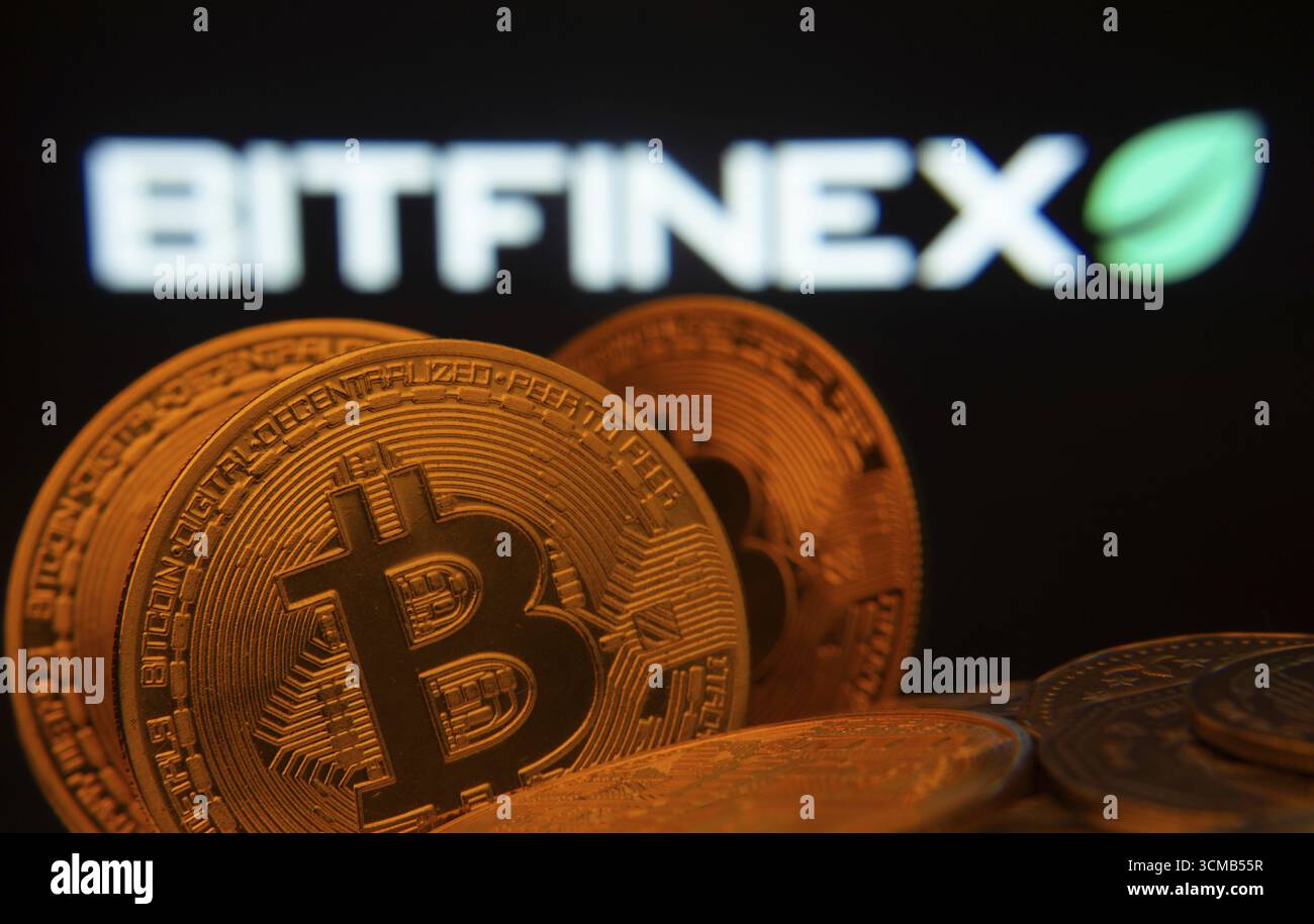 Dhaka, Bangladesh- 15 giugno 2025: Primo piano delle monete Bitcoin con il logo Bitfinex visibile su uno schermo sullo sfondo Foto Stock