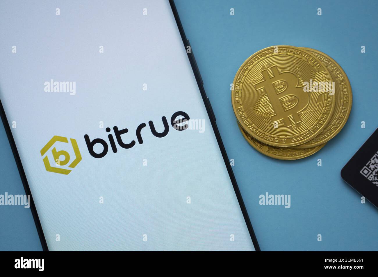 Dhaka, Bangladesh- 3 settembre 2025: Logo Bitrue sullo schermo dello smartphone vicino alla moneta Bitcoin e codice QR su sfondo blu Foto Stock