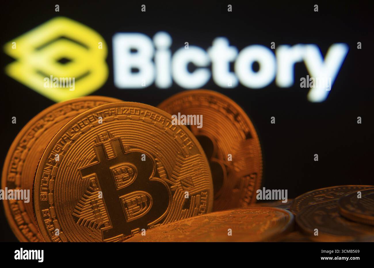 Dhaka, Bangladesh - 09 settembre 2025: Primo piano delle monete Bitcoin con il logo Bictory visibile su uno schermo sullo sfondo Foto Stock