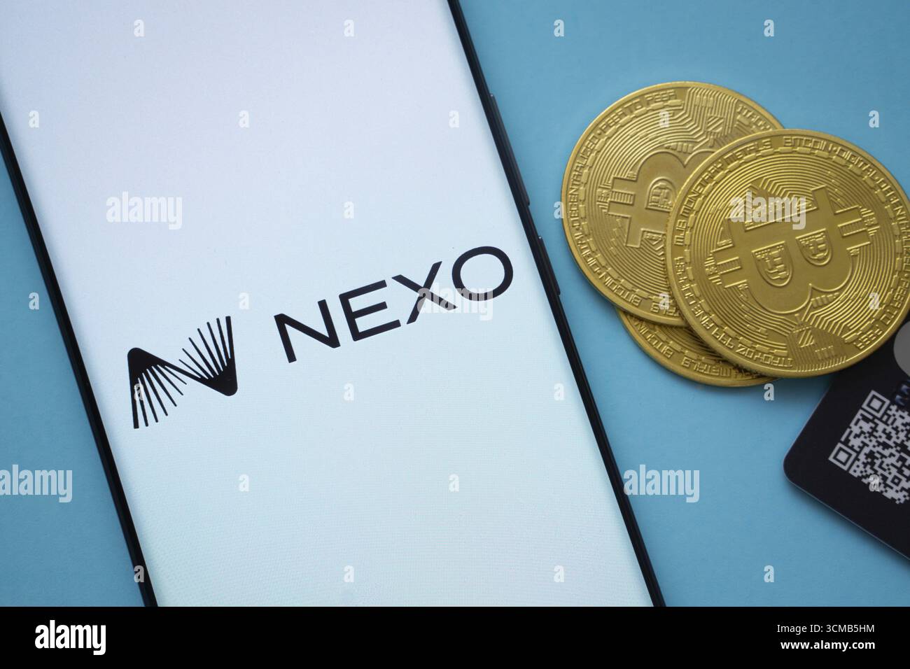 Dhaka, Bangladesh - 06 settembre 2025: Logo Nexo sullo schermo dello smartphone vicino alla moneta Bitcoin e codice QR su sfondo blu Foto Stock