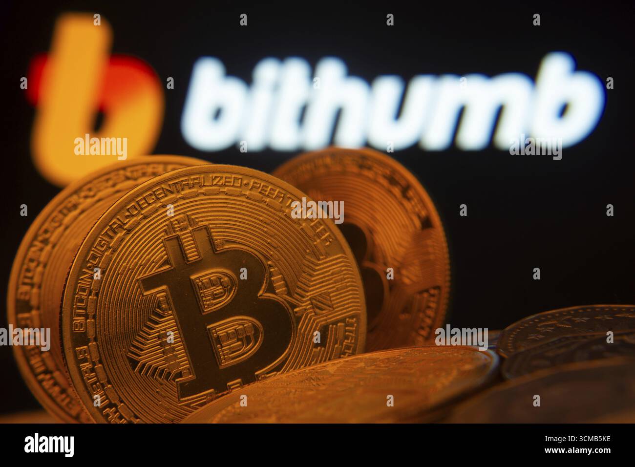 Dhaka, Bangladesh - 7 maggio 2025: Primo piano delle monete Bitcoin con il logo Bithumb visibile su uno schermo sullo sfondo Foto Stock