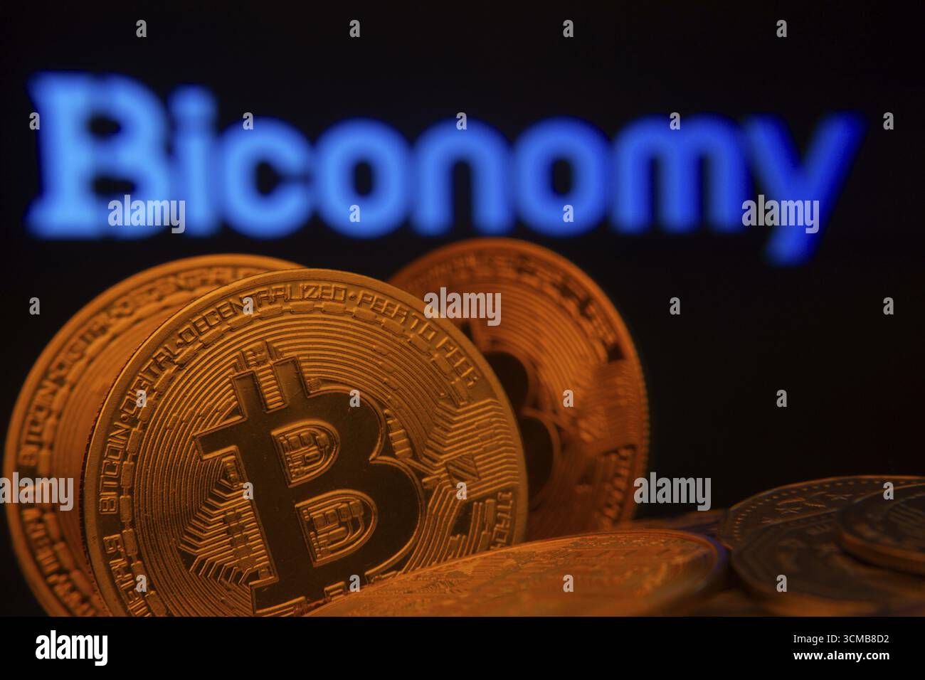 Dhaka, Bangladesh- 03 set 2025: Primo piano delle monete Bitcoin con il logo Biconomy visibile su uno schermo sullo sfondo Foto Stock
