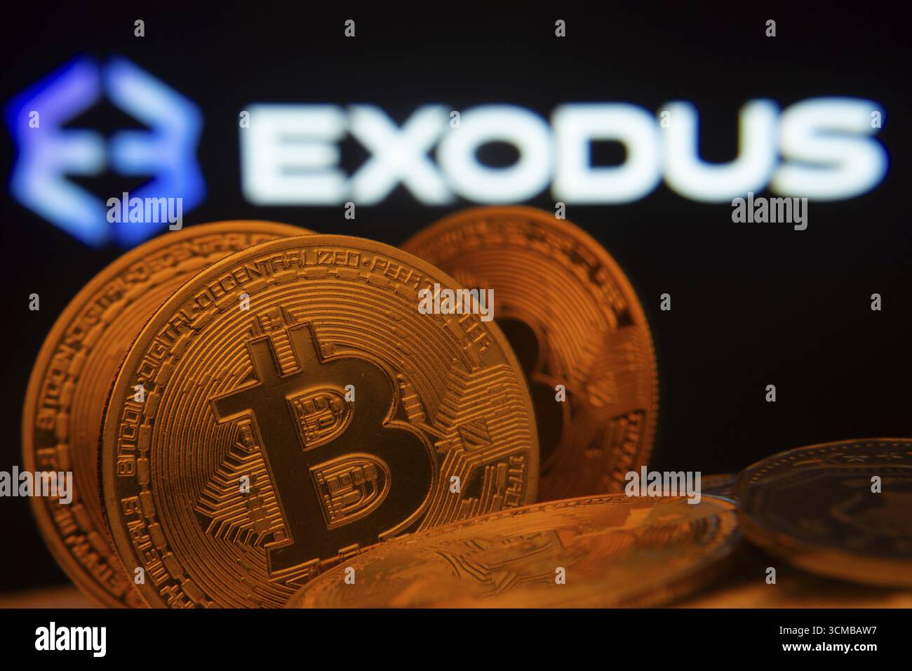 Dhaka, Bangladesh - 06 settembre 2025: Primo piano delle monete Bitcoin con il logo Exodus visibile su uno schermo sullo sfondo Foto Stock