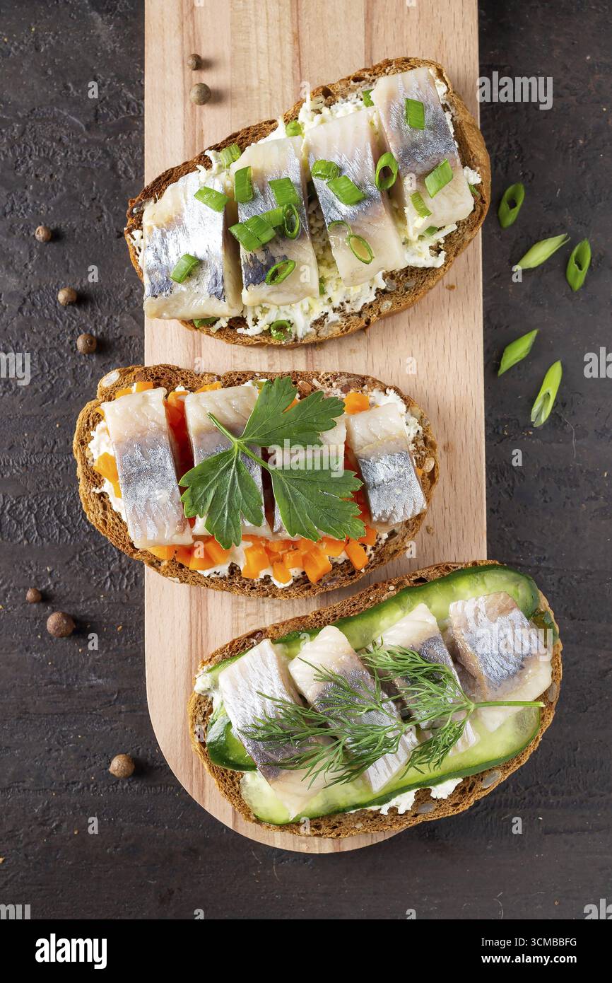 Panini con aringhe su tavola di legno su un piatto di pietra marrone Foto Stock