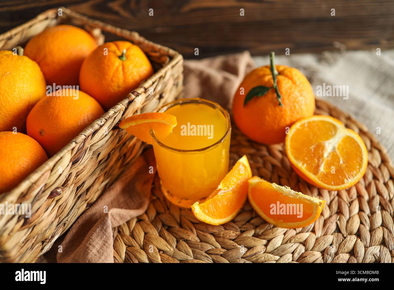 Bicchiere di succo d'arancia, arance a fette e un cestino di arance. Le arance sono luminose e fresche. Foto Stock
