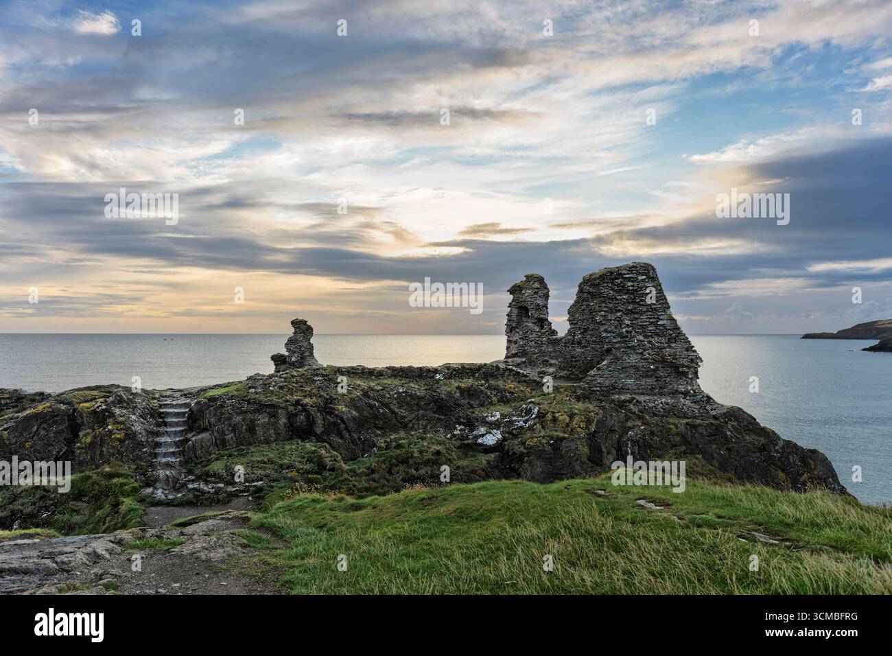 Storico Castello Nero a Wicklow, affacciato sul Mare d'Irlanda, con rocce aspre, pendii verdi e un cielo cinematografico. Foto Stock