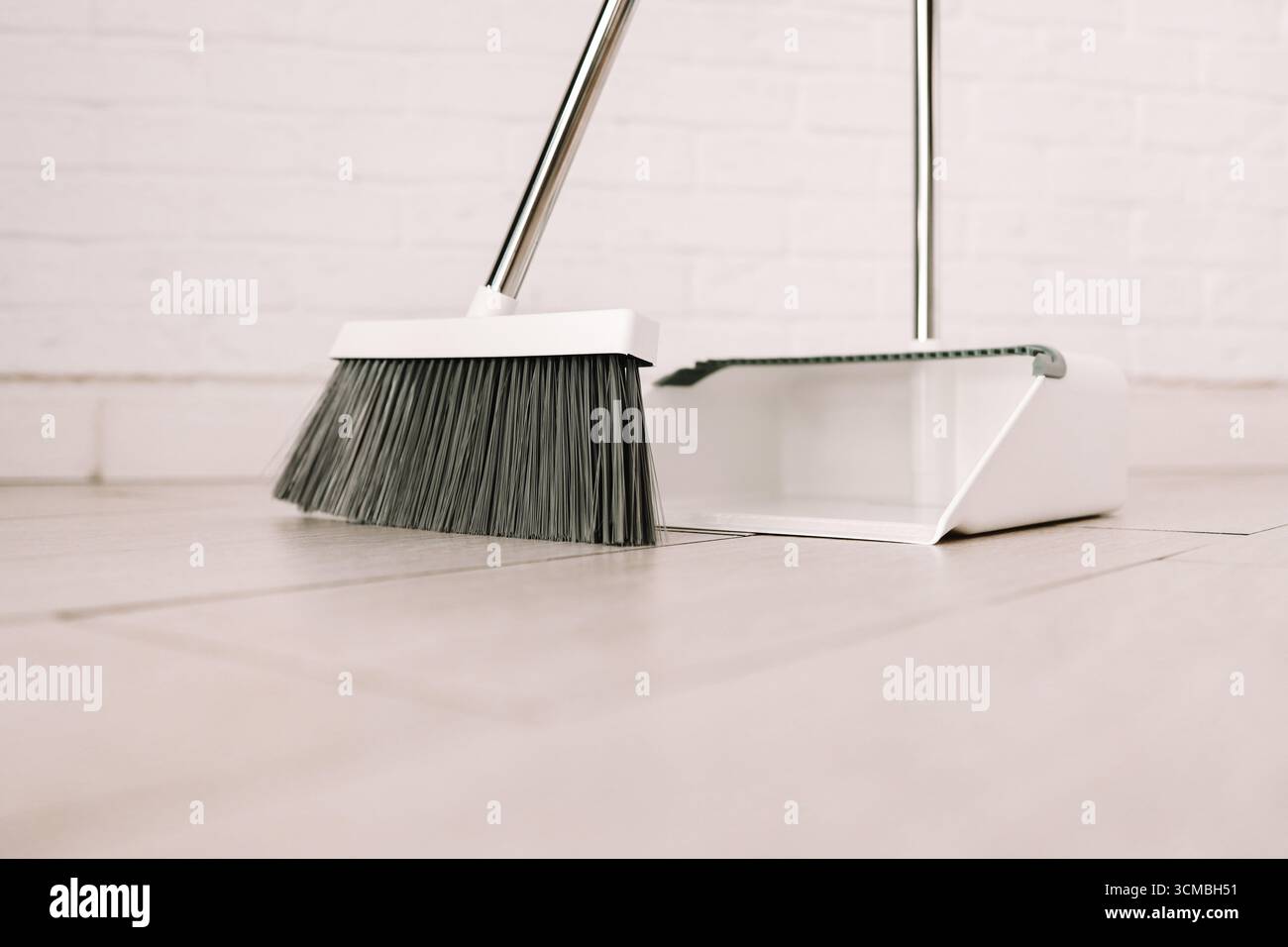 Set elegante bianco per pulire la casa, la scopa e la paletta da vicino su sfondo bianco. Foto Stock
