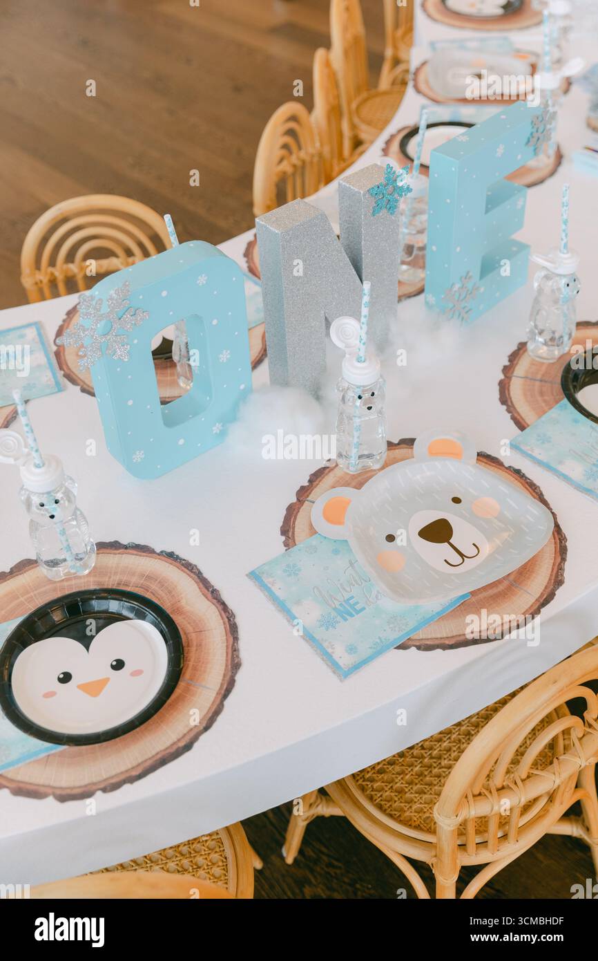 Tavolino colorato adornato con piatti e decorazioni a tema animale, pronto per una festa invernale per i bambini. Foto Stock