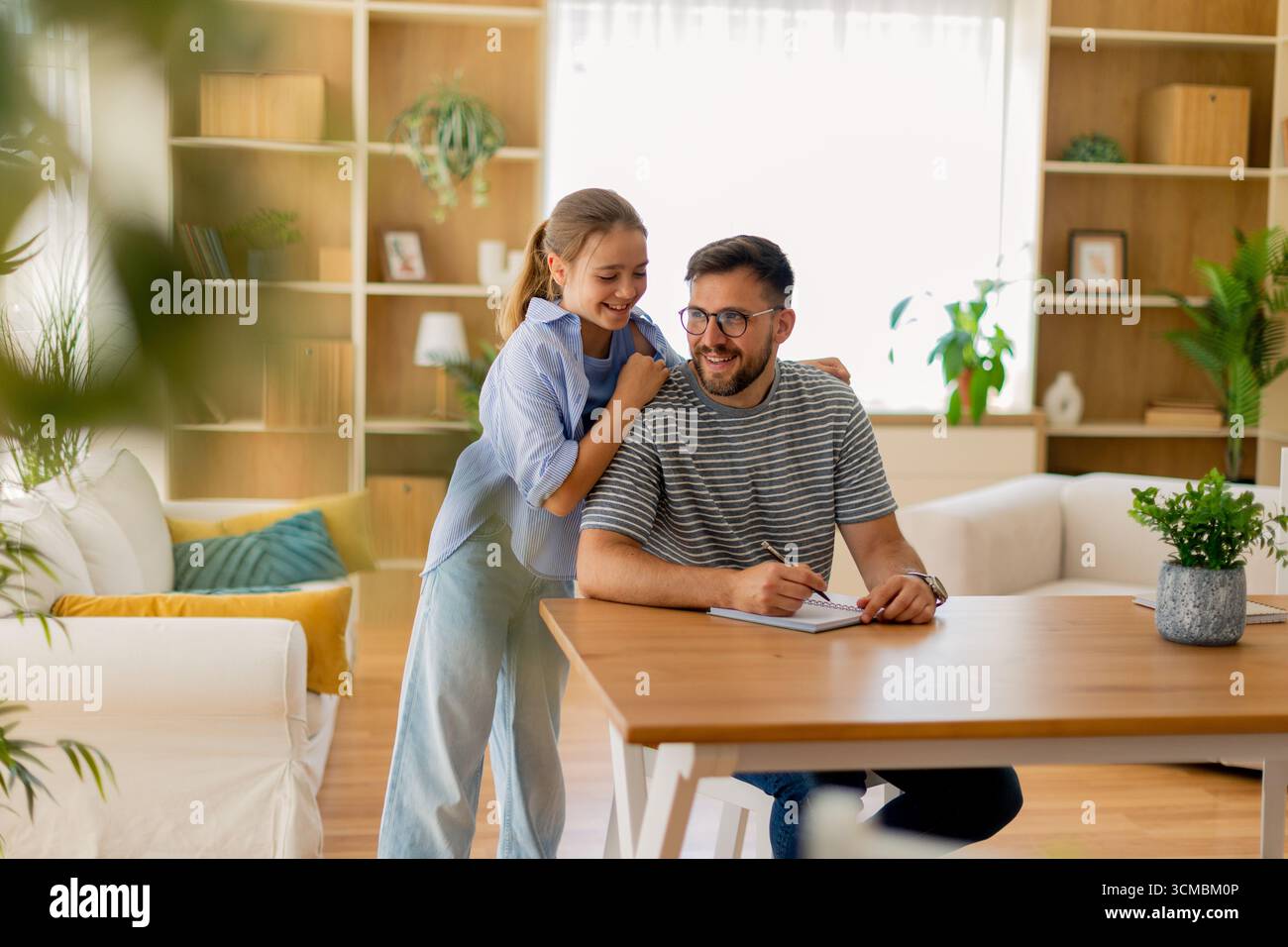 Un padre e una figlia condividono un momento delizioso nel loro accogliente salotto mentre si impegnano in attività creative insieme, mostrando il loro legame e jo Foto Stock