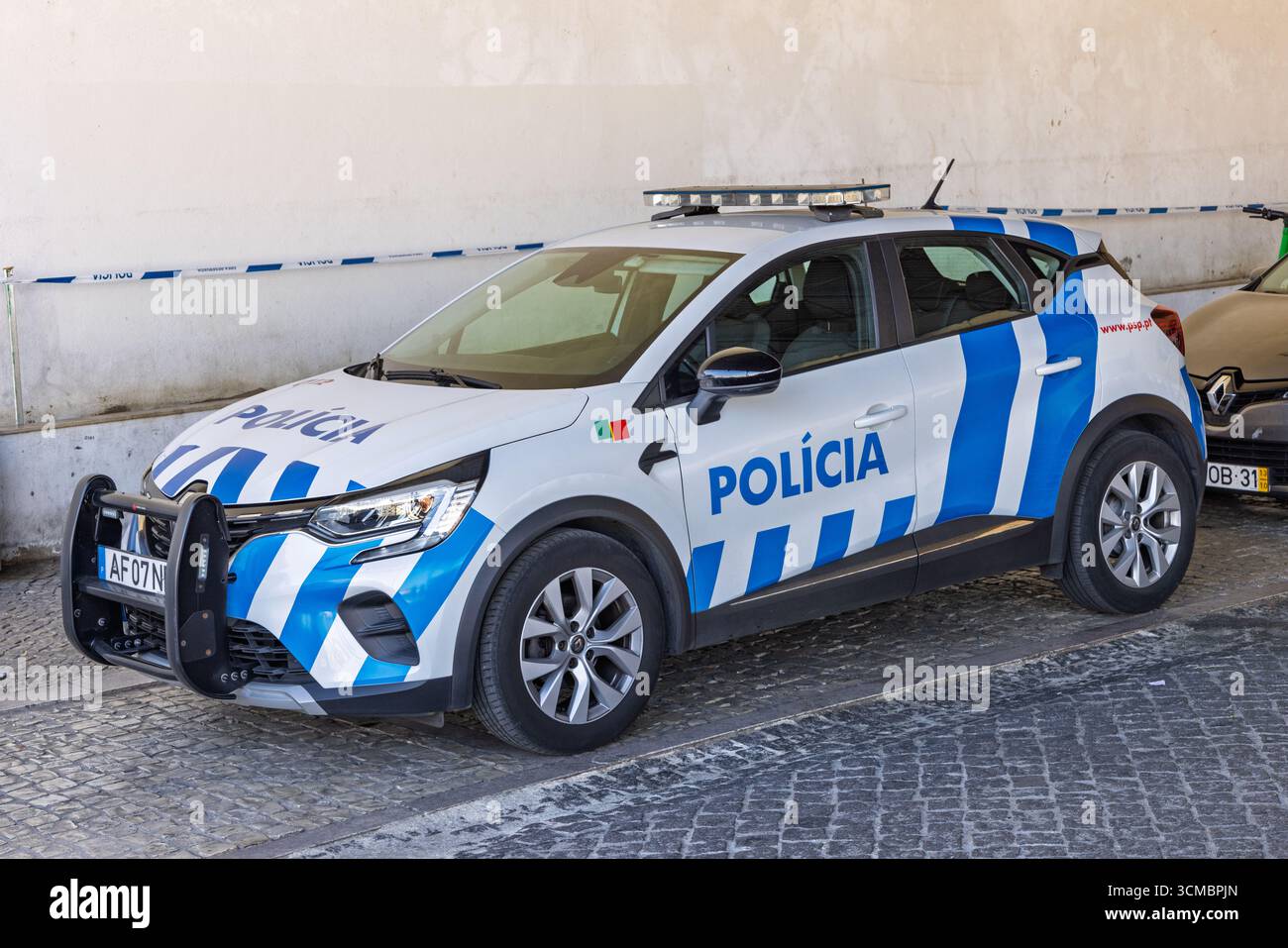 Un'auto della polizia portoghese con un design a strisce blu e bianche è parcheggiata a Lisbona. Il veicolo è dotato di una barra di toro e la parola "Polícia" sul lato. Foto Stock