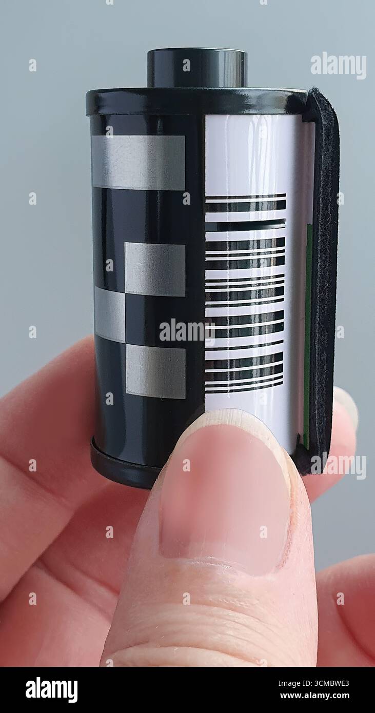 Dita femminili che tengono in mano la cartuccia per pellicole fotografiche Vintage da 35 mm. Negativo per fotocamera su sfondo semplice, pellicola fotografica vecchia scuola, elemento Foto Stock