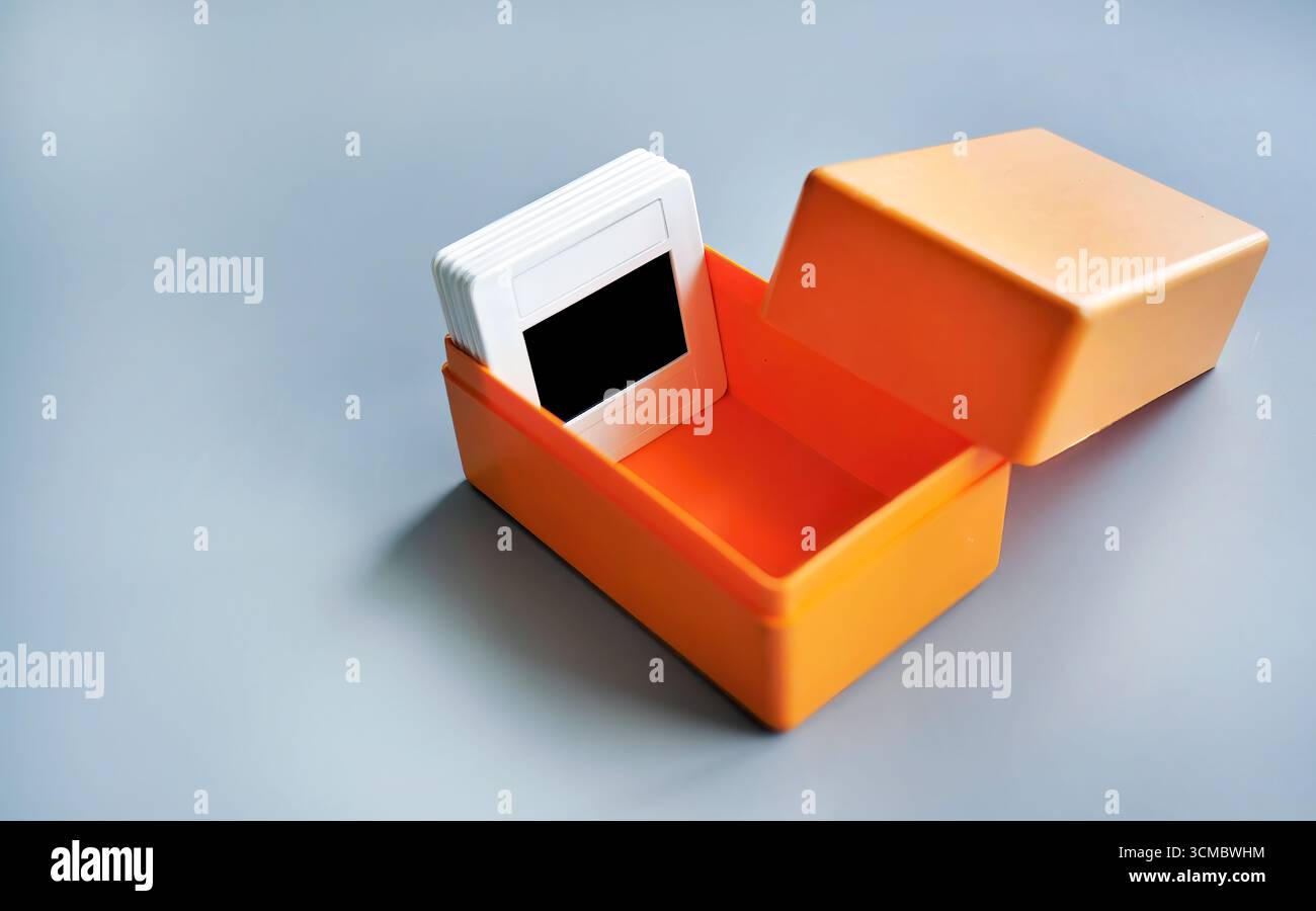 Supporto per telaio scorrevole in plastica bianca per pellicola per vetrini contenuto in una scatola di plastica arancione con sfondo semplice, nostalgia retrò, fotografia Foto Stock