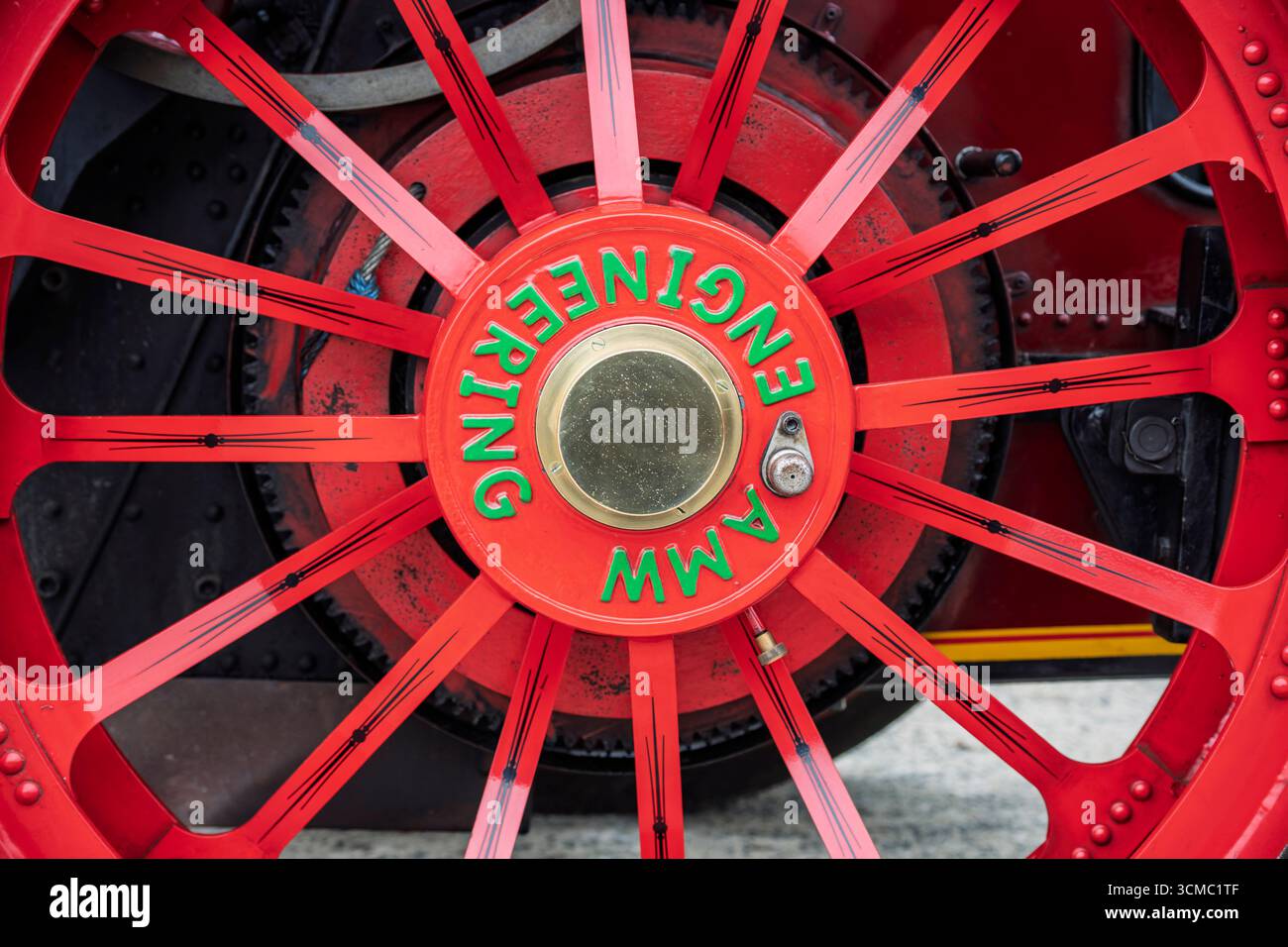 Primo piano della ruota del motore a vapore, con razze rivettate, verniciato di rosso con mozzo AMW Engineering, dettaglio Coolgreany Parade. Foto Stock