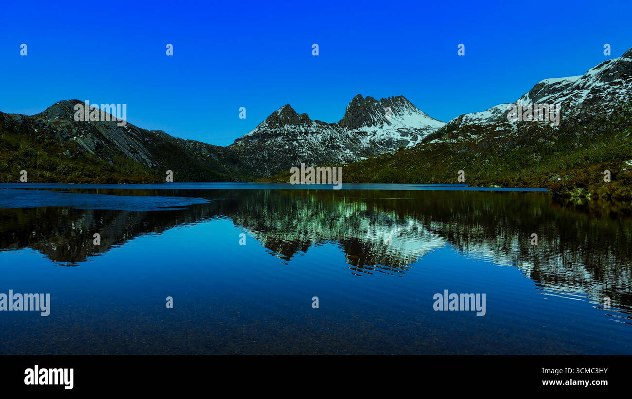 Perfetto riflesso a specchio su un tranquillo lago di montagna blu all'ora blu; acqua cristallina, cielo pastello e tranquilla simmetria alpina. Illustrazione Vettoriale