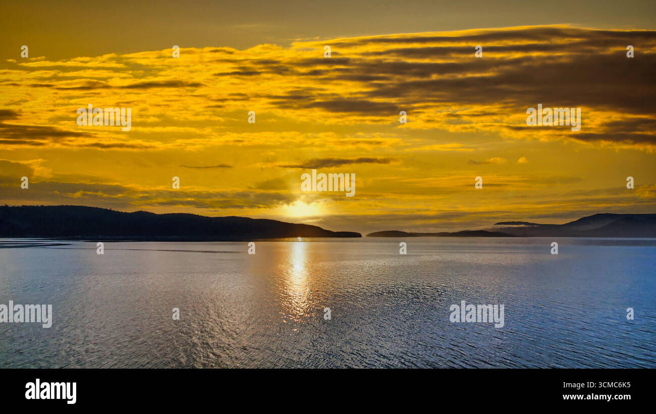 Tramonto sul Pacifico alle isole San Juan, Washington; cielo pastello, orizzonte luminoso e calmo mare di Salish con sagome isolane. Illustrazione Vettoriale