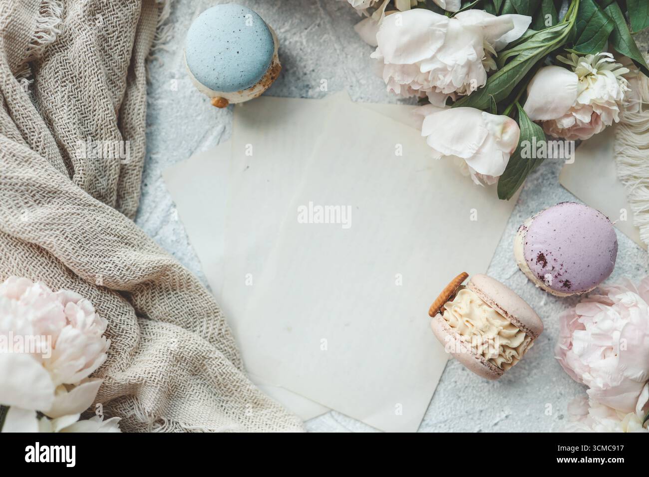 Biglietto d'auguri con posto per il testo, le peonie bianche e i dolci macaron dall'alto. Foto Stock