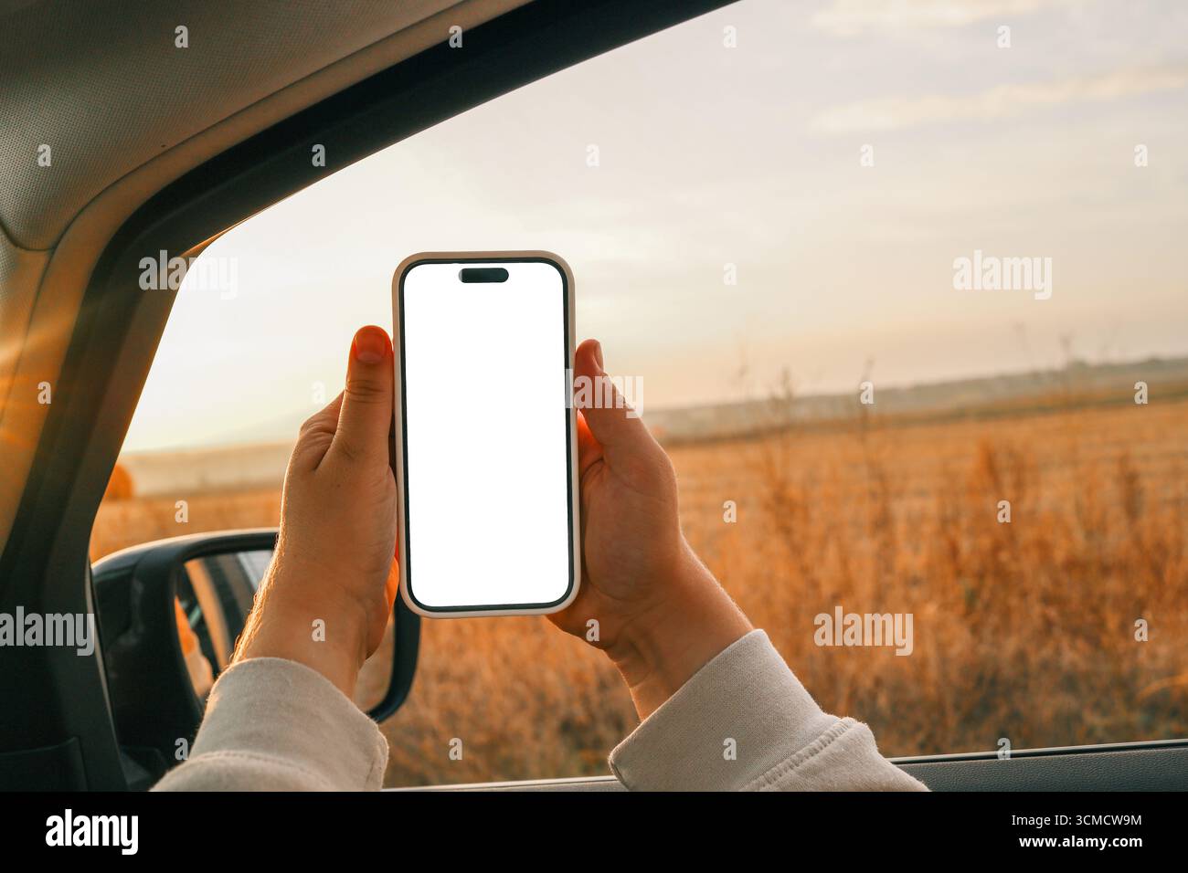 Telefono in mano con schermo isolato sullo sfondo di una strada autunnale. Foto Stock