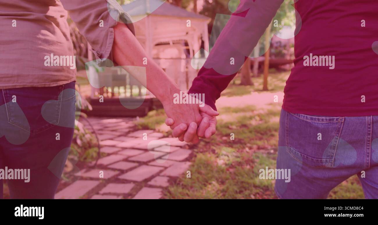 Coppia matura che cammina tenendo le mani su un sentiero in pietra nel giardino sul retro, avvicinandosi al gazebo in legno Foto Stock Coppia matura che cammina tenendo le mani su un sentiero in pietra nel giardino sul retro, avvicinandosi al gazebo in legno Foto Stock