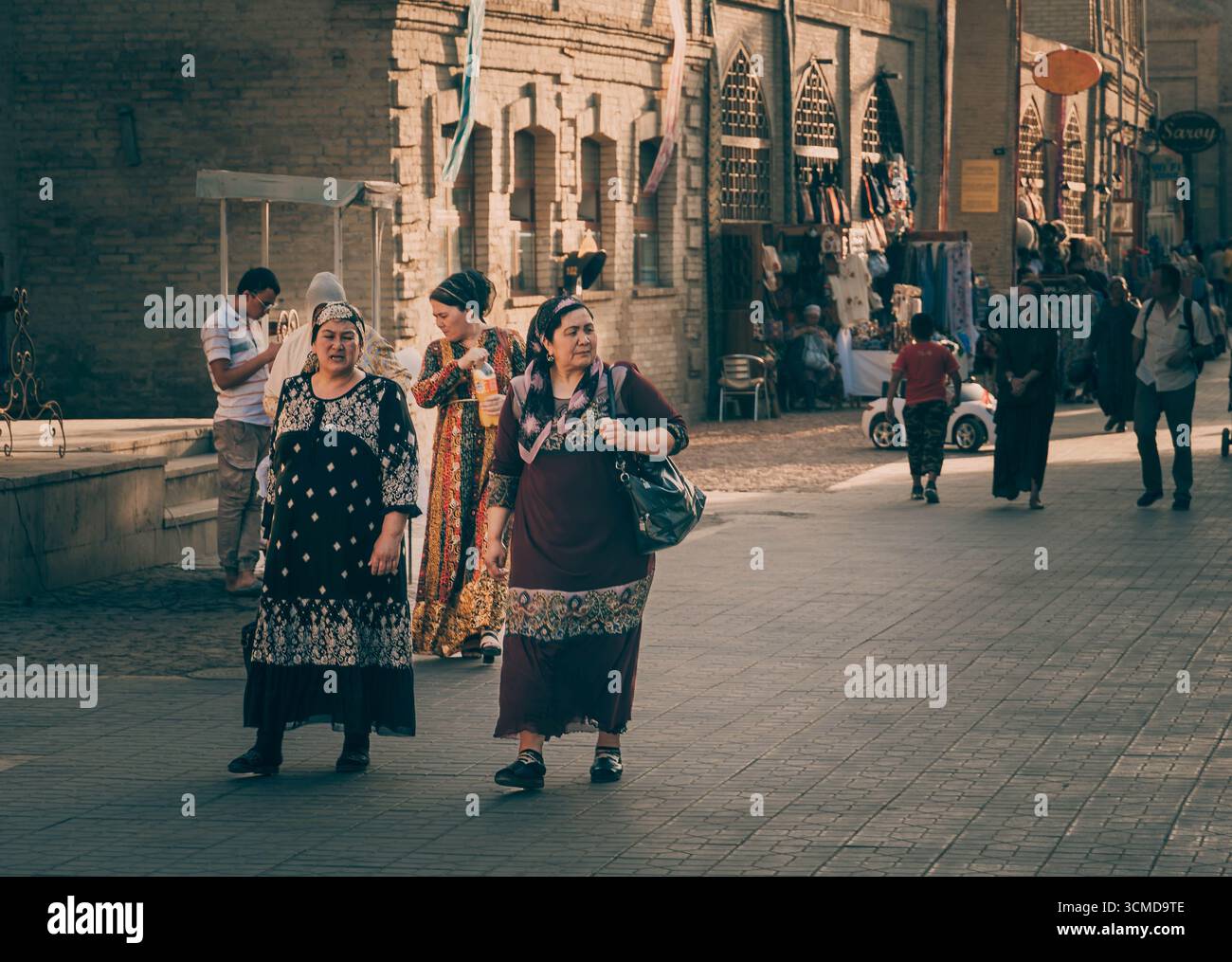 Il giovane uzbeko sfoglia le ceramiche in una bancarella a Bukhara, Uzbekistan, tra vasi di argilla e cesti intrecciati, indossando un gilet e jeans Foto Stock