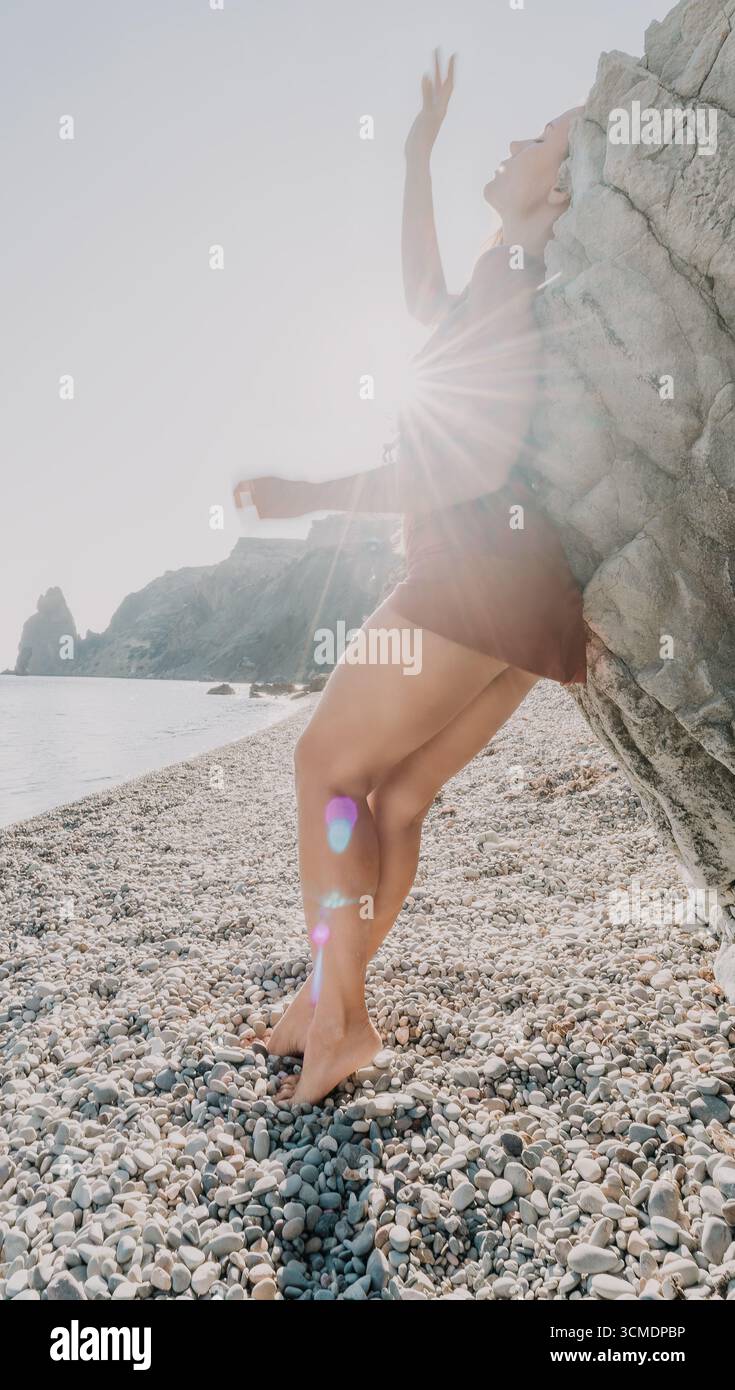 Woman in a Dress si appoggia a Rock on a Pebble Beach Foto Stock