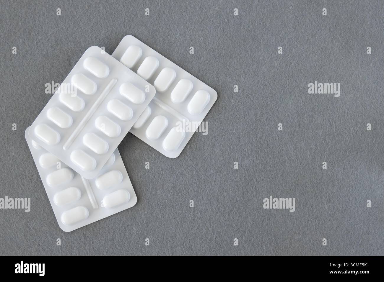 Molte pillole mediche e farmaci in confezione di plastica bianca su sfondo grigio. Concetto di assistenza sanitaria. Spazio per il testo. Foto Stock