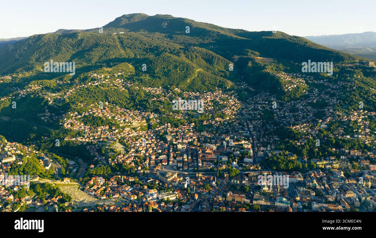 Foto in droni della città di Sarajevo con la montagna Trebevic che torreggia sopra, mostrando il paesaggio urbano che si fonde con la natura Foto Stock