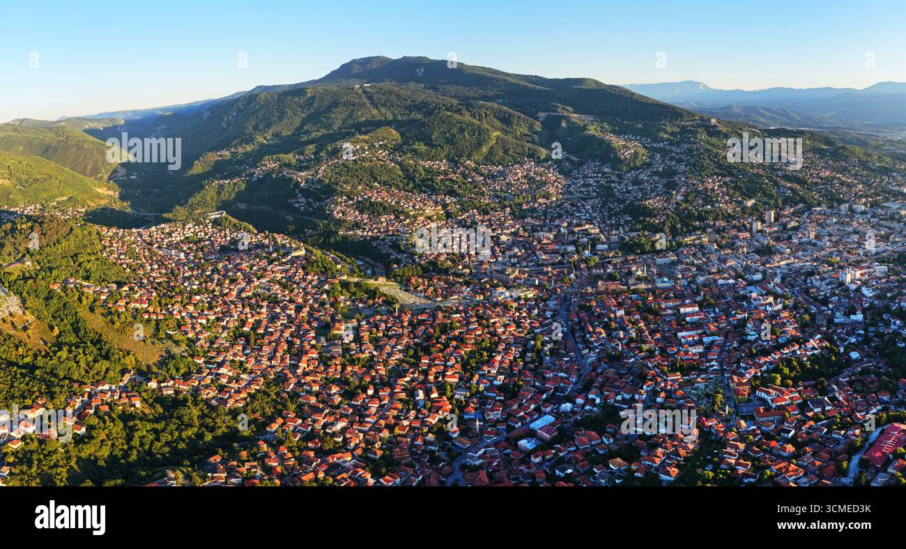 Foto panoramica della città vecchia di Sarajevo con tetti rossi e verdi colline alla luce del sole dorato Foto Stock