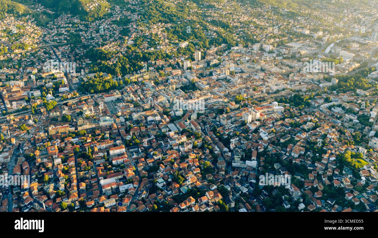 Prospettiva aerea del nucleo storico di Sarajevo con stradine strette, vecchie case e monumenti centrali circondati da colline Foto Stock
