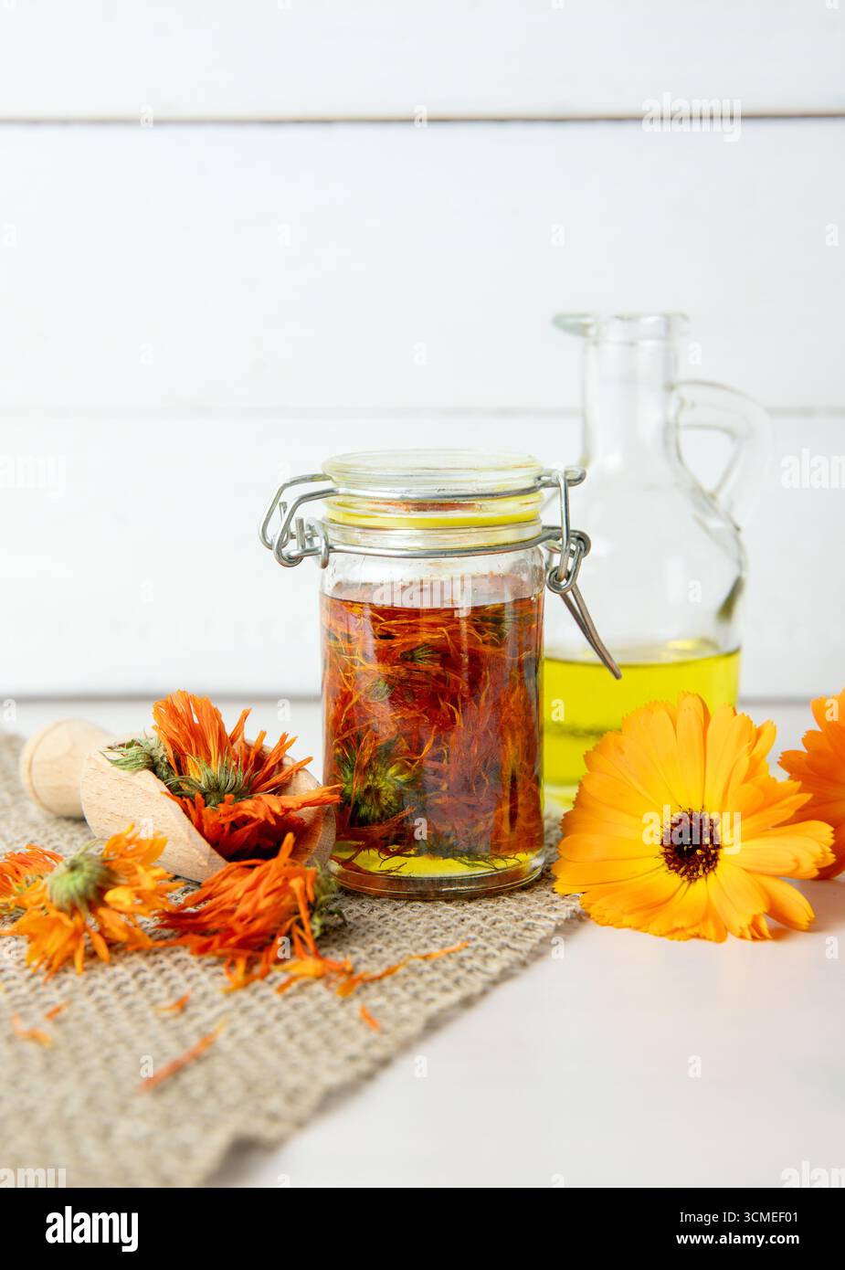 Preparazione di Calendula officinalis, olio per infusione fredda di calendula comune in vaso di vetro. I fiori secchi sono immersi nell'olio d'oliva a temperatura ambiente. Foto Stock
