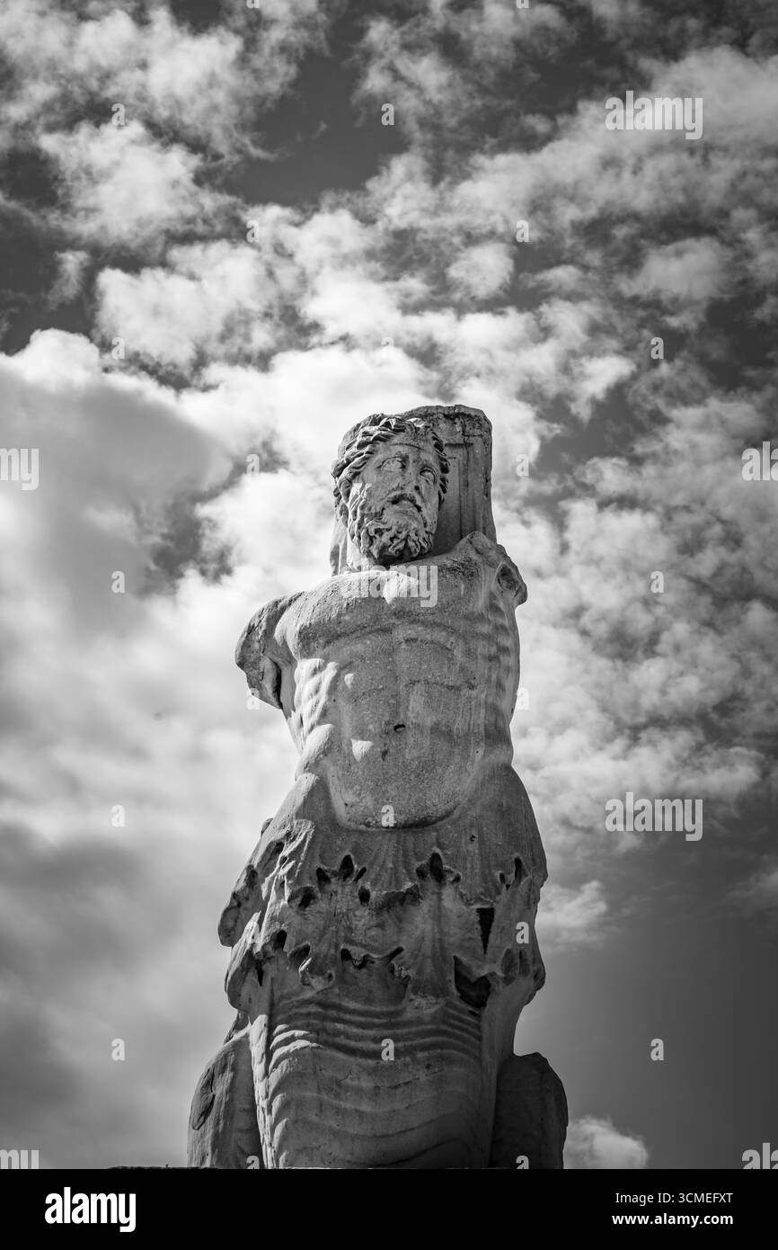 Vista monocromatica della statua di marmo di un Tritone dall'Odeione di Agrippa, esposta nell'antica Agorà di Atene, Grecia. Maggio 2025 Foto Stock