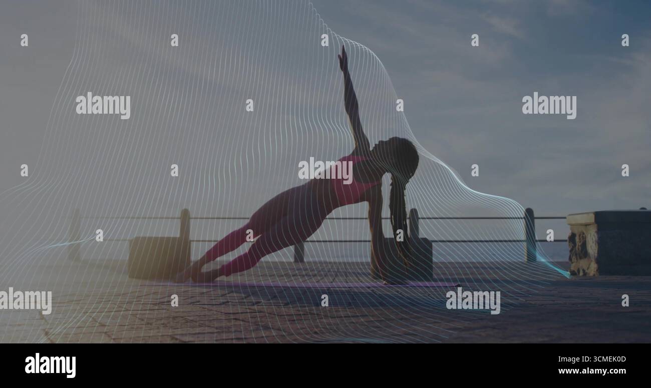 Donna che tiene la tavola laterale in posa in abbigliamento sportivo su un molo di pietra all'alba, con tappetino, blocco, ringhiera Foto Stock