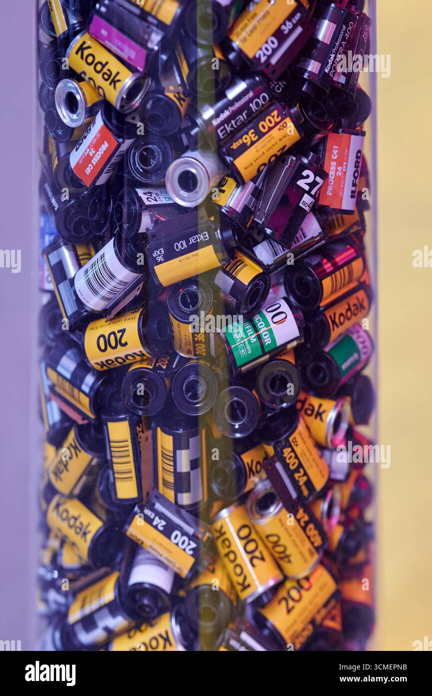 Una vivace collezione di rotoli di pellicole fotografiche assortiti all'interno di una scatola trasparente, che mette in risalto la diversità dei marchi Kodak e Fujifilm con il viola e la stella forti Foto Stock