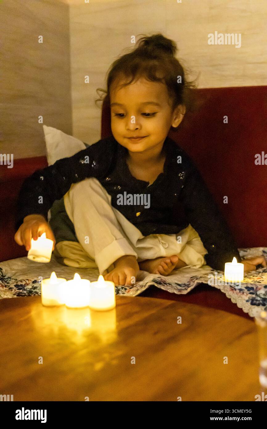 adorabile bimbo eccitato al festival diwali con candele artificiali al coperto Foto Stock