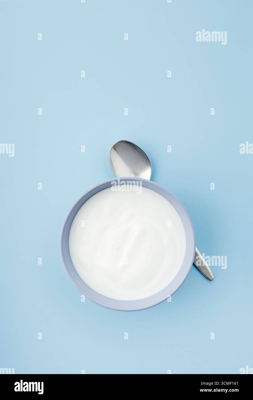 Una ciotola di yogurt naturale al latte di capra su sfondo blu liscio Foto Stock