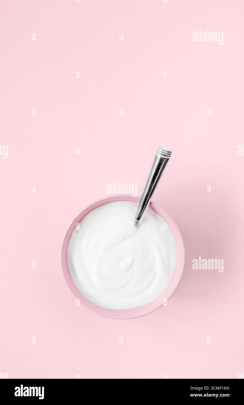 Una ciotola di yogurt naturale al latte di capra su sfondo rosa Foto Stock