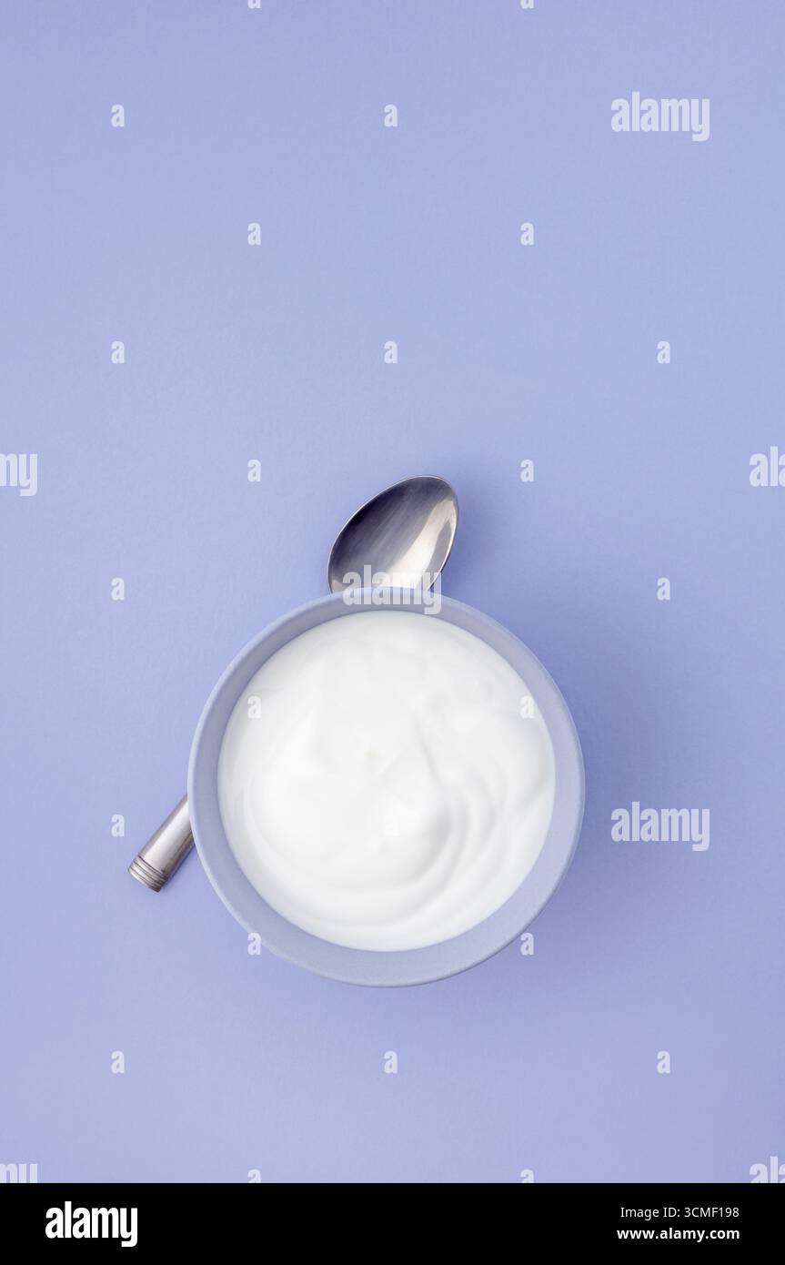 Yogurt naturale fresco in una ciotola blu su sfondo blu Foto Stock