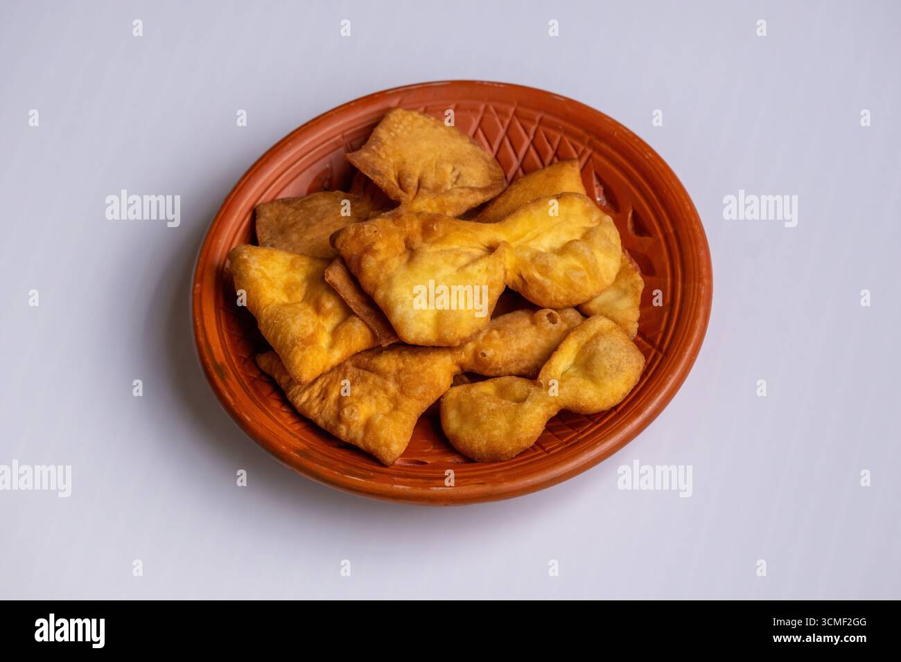 Projapoti Pitha del Bangladesh fatti in casa o torta a farfalla su un piatto di argilla. Questo dolce e croccante spuntino tradizionale è perfetto per il tè o per festeggiare Foto Stock