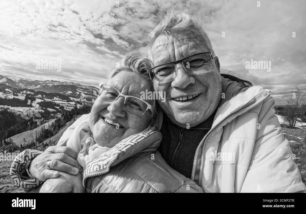 Felice coppia anziana che si prende selfie durante la giornata invernale di trekking in cima alla montagna - concetto di stile di vita per anziani con amore e gioia - concentrazione sui volti Foto Stock