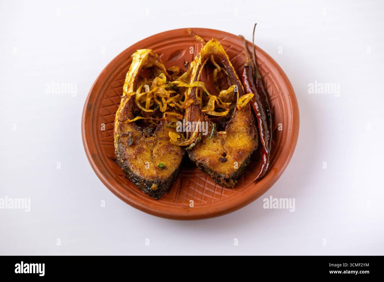 Frittura croccante di pesce hilsha (bhaja ilish) servita con peperoncini rossi fritti su un piatto rustico di argilla. Un tradizionale, iconico e delizioso pasto bengalese. Foto Stock