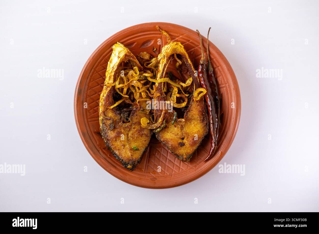 Deliziosa frittura di pesce Hilsa (Ilish bhaja) con peperoncini rossi fritti su un piatto rustico di argilla, che mostra un tradizionale e popolare pasto bengalese. Vista dall'alto Foto Stock