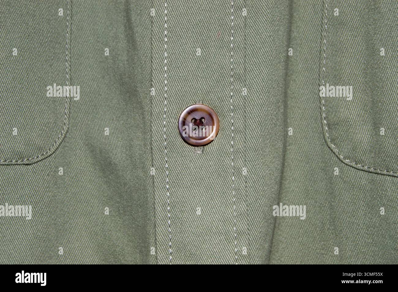 Dettaglio ravvicinato di una camicia verde stile militare da uomo che mostra due tasche con pattina sul petto e bottoni. Vista frontale del tessuto di camicia casual in cotone verde oliva tex Foto Stock