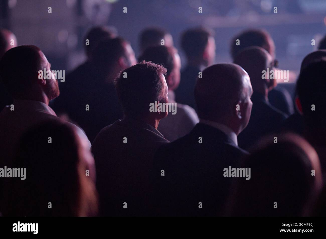 Profilo del pubblico della conferenza vista posteriore a Gdynia, luci viola da palcoscenico, teleobiettivo paesaggistico con profondità ridotta, atmosfera di attesa, ideale anche per gli affari Foto Stock